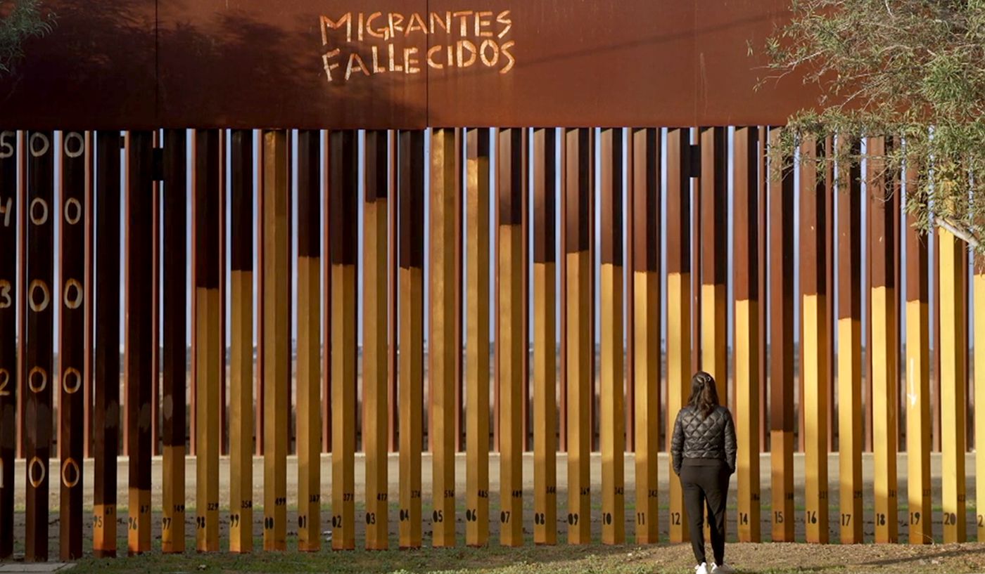 The Spanish words “migrantes fallecidos”, meaning “deceased migrants”, are scrawled onto a portion of the US-Mexico border wall.