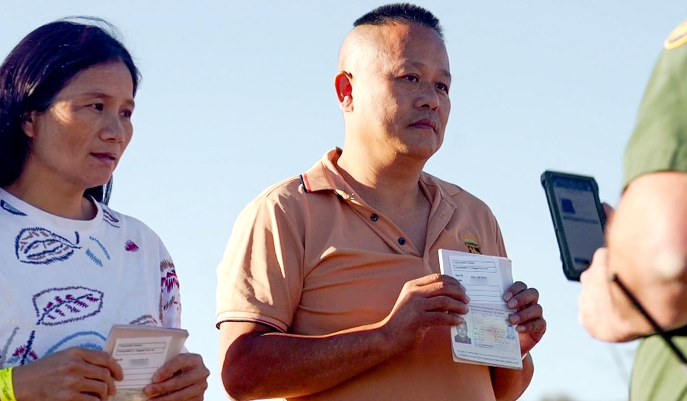 A Chinese couple presents their passports before a US border patrol official.